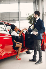 Woman buying the car. Lady in a car salon. Manager with a clients