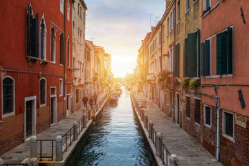 Fototapeta na wymiar Street canal in Venice, Italy. Narrow canal among old colorful brick houses in Venice, Italy. Venice postcard