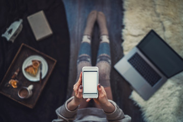 Woman using smartphone for browsing internet store at home. Online shopping conceptspace for text. Mood winter. Seasonal holidays. Merry Christmas and New Year. Top view. Toned image. Selective focus.
