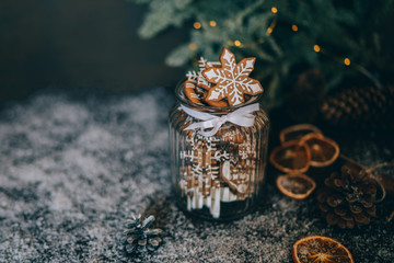 Homemade gingerbread in the glass jar with fir branches on the background, spices and decor. Holidays, winter, Christmas presents concept. Merry Christmas and Happy Holidays. Toned image. Soft focus.