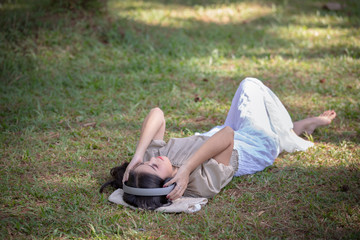 women asian girl with headphones listening Bluetooth digital music in the park