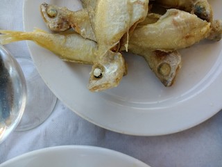 Delicious white plate serving of fish with heads in tempura delicate batter fried, freshly caught...