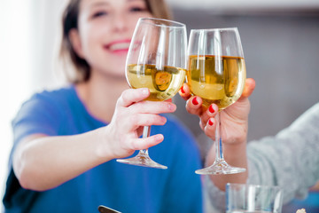 Two women drinking wine in glass at home.