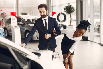 Couple buying the car. Lady in a car salon. Man in a suit