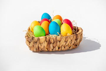 Gefärbte Ostereier im Korb im Sonnenlicht vor weißem Hintergrund
