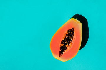 Fresh cut papaya with ceeds on blue background.
