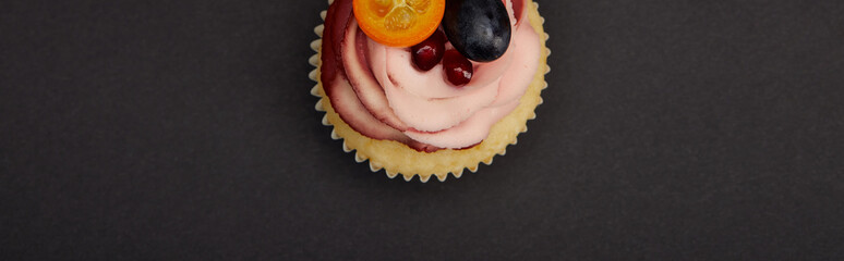 panoramic shot of cupcake with cream and fruits on black surface