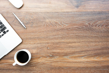 Wood office desk table with laptop computer, cup of coffee and supplies. Top view with copy space, flat lay.