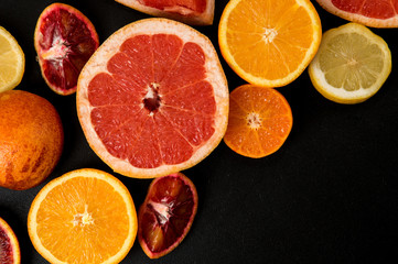 Top view, macro. Sliced colorful citrus on a dark background. Copy space right below.