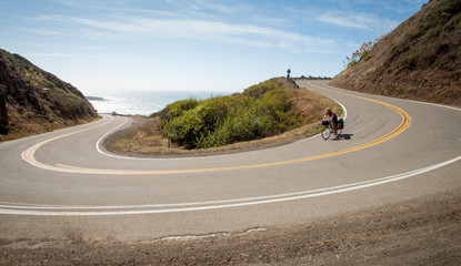 Women descending hairpin turn on the California Coast Highway on Cross country bike with panniers. 