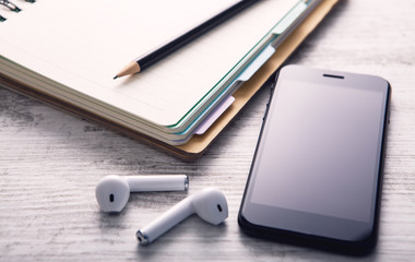notebook, smartphone and wireless headphones on a white, wooden background