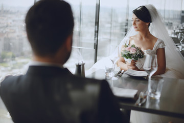The stylish and elegant bridegroom and his pretty wife sitting in a restaurant