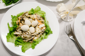 Gourmet salad in a white plate. Slices of cheese, eggs, lettuce. White plate on white table. Food. Holiday. flat lay. top view.