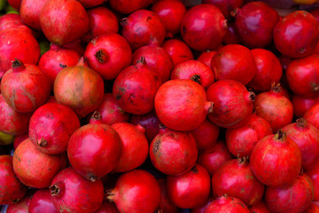 Red ripe pomegranates as background. A pile of pomegranates on a counter, close up.