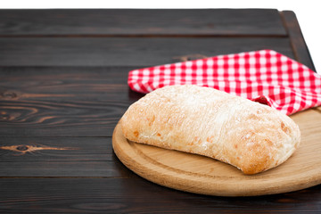 Loaf of ciabatta bread on a cutting board on the dark wooden table