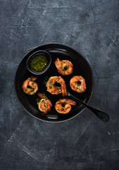 Shrimp prawns fried on a plate with marinade sauce on a black concrete background, top view flat lay