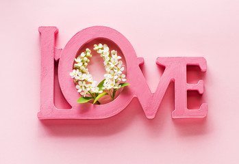 Word love and white spring flowers on a pink background. Creative concept with inscription love
