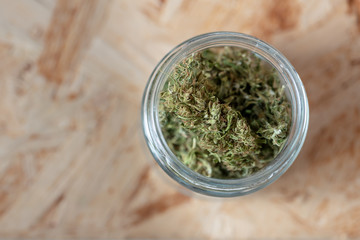 a glass jar filled with marijuana buds, medical hemp with low CBD content