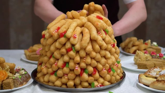 Chak-chak traditional asian sweet dessert - fried dough with honey. Oriental sweets. The waiter in the restaurant lays out the dessert in plates. Traditional dessert on nikah Muslim wedding.