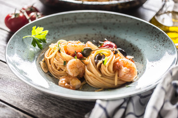 Pasta spaghetti on plate and pan with shrimp tomato sauce toatoes and herbs. Italian or...