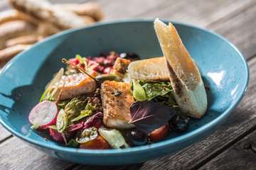 Fresh vegetable salad with roasted salmon olive oil and baguette
