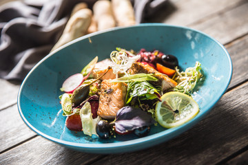 Fresh vegetable salad with roasted salmon olive oil and baguette