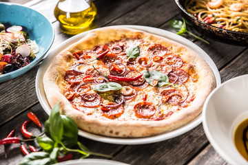 Pizza salami diavola with red onion basil and chili pepper