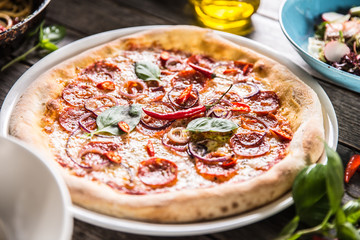 Pizza salami diavola with red onion basil and chili pepper