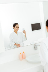selective focus of attractive and happy young woman taking photo in bathroom
