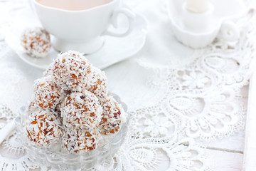 Useful candies of dried fruits in coconut chips in the form of balls on a white table, horizontal, copy space