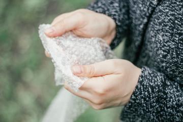 Female hands popping the bubbles in bubble wrap. Selective focus