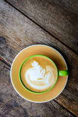 A cup of coffee  in a green cup on wooden background