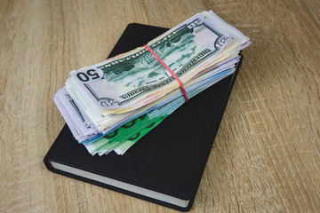 American dollars, euros, rubles are on a black notebook. The concept of a financial plan for the year, investment or saving money. wooden background