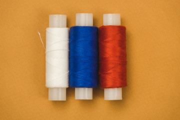 red white and blue threads on an orange background