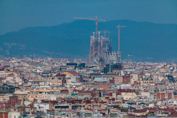 Aerial view of the Barcelona city with the Temple Expiatori de la Sagrada Familia (Expiatory Church of the Holy Family) in the distance on the background of mountains at twilight, Spain