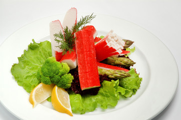 Crab sticks on a plate with salad on white background
