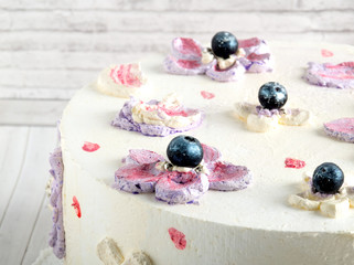 White decorated homemade cake with blueberry on wooden background close up
