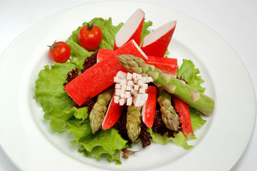 Crab sticks on a plate with lettuce and tomatoes on a white background