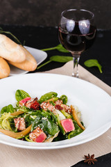 Salad with corn, meat, salmon, green leaves, tomatoes, oil and spices