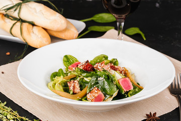 Salad with corn, meat, salmon, green leaves, tomatoes, oil and spices