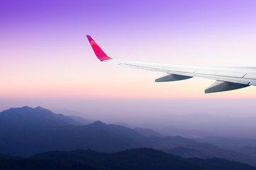 Fototapeta na wymiar cloudy sky and airplane wing as seen through window of an aircraft