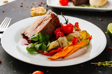 Fried pork with vegetables: green beans, carrots, paprika, garlic, greens, tomato and a glass of red wine,