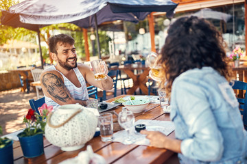 Smiling couple sitting in a restaurant enjoying in beer and conversation.