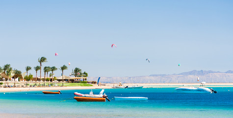 Fototapeta na wymiar hotel with palm trees on the Red Sea in Egypt Dahab with boats and kite surfers