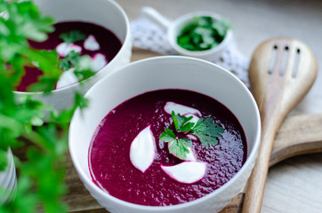 Vegetarian borscht soup in a bowl with cream and parsley as a traditional dish on dinner.