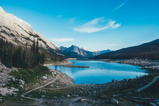 Ein blauer See in einer Berglandschaft umringt von Stra&szlig;en und B&auml;umen