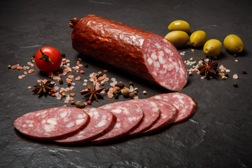 closeup dry cured salami sausage with olives and tomato