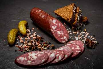 top view of dry cured salami sausage with rye bread and pickled cucumbers
