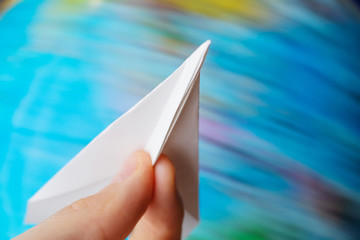 Globalization, world, travel concept, world society - paper airplane in hand close up on a globe background. Countries and continents, air travel, world tour.