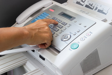 Hand man are using a fax machine in the office Business concept  - obrazy, fototapety, plakaty